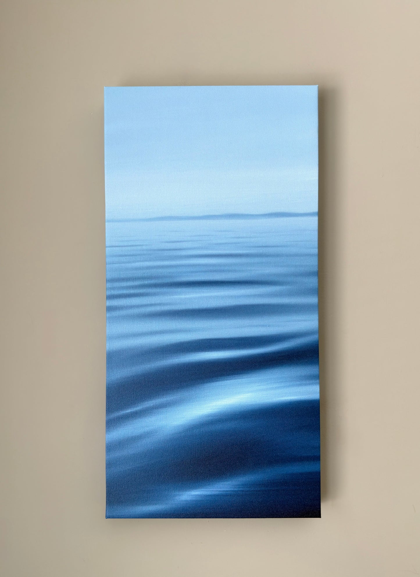 Abstract blue waterscape artwork on a beige wall
