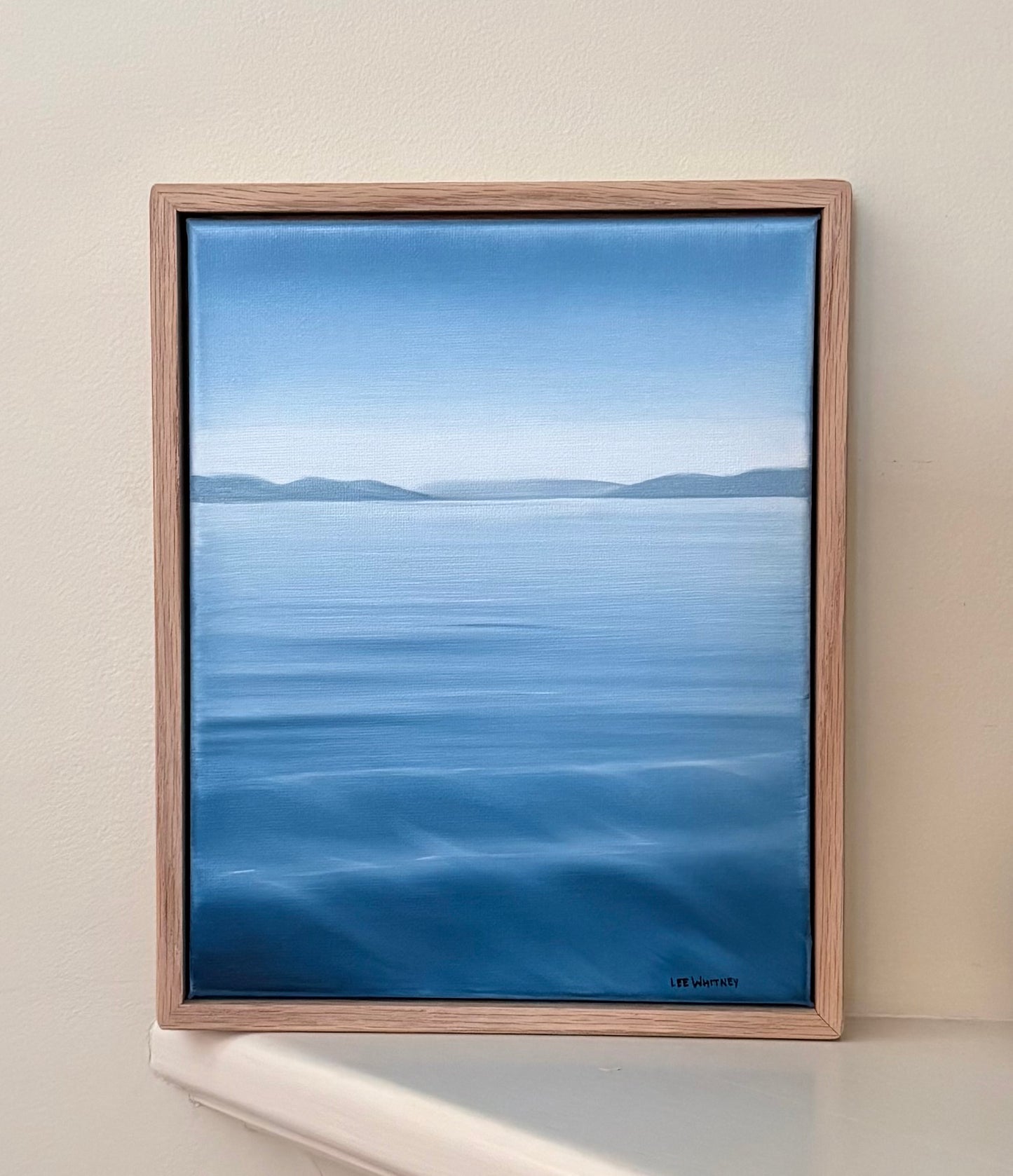 Framed artwork of a blue landscape on a beige wall