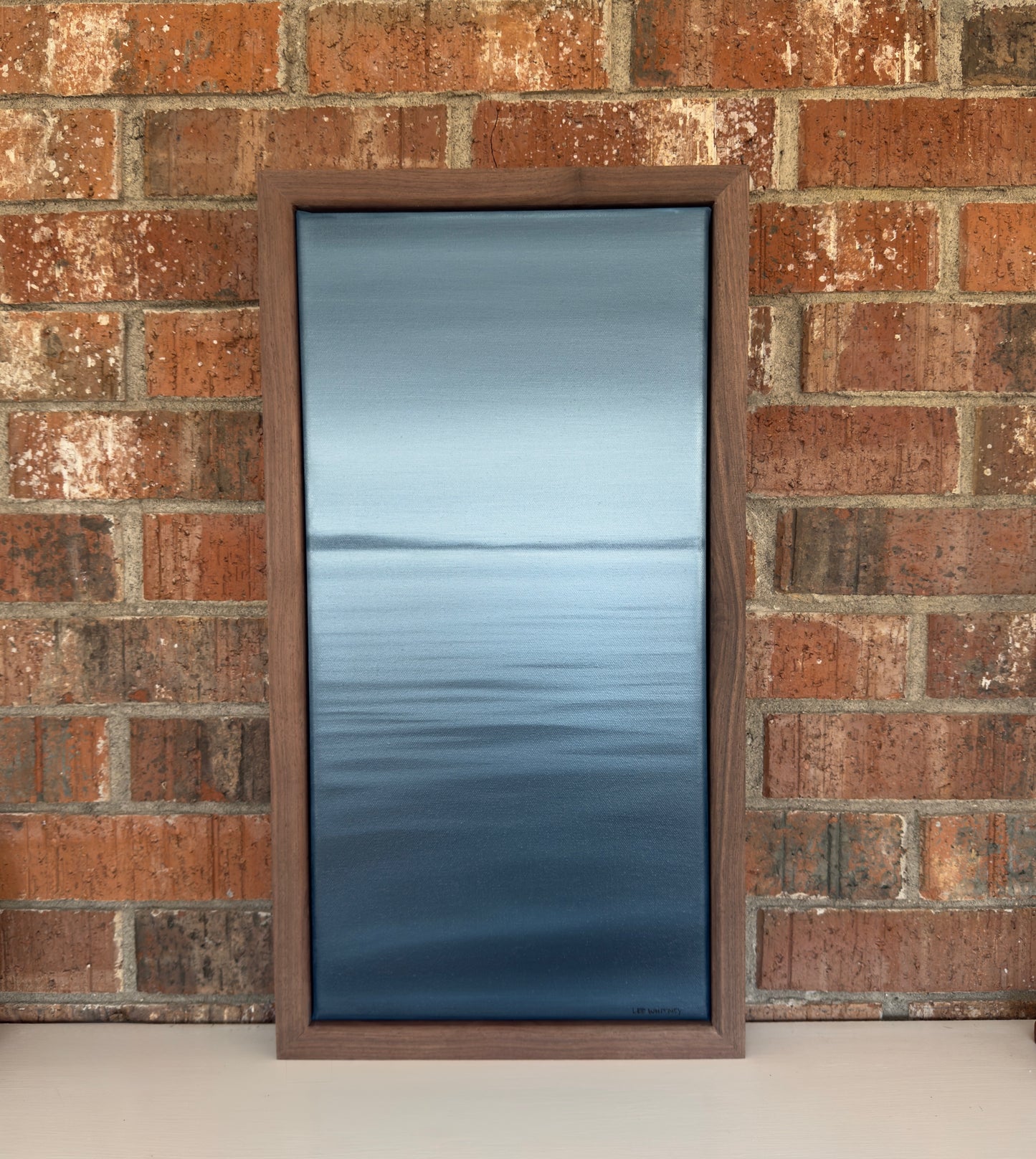 Rectangular painting with wooden frame on a brick wall