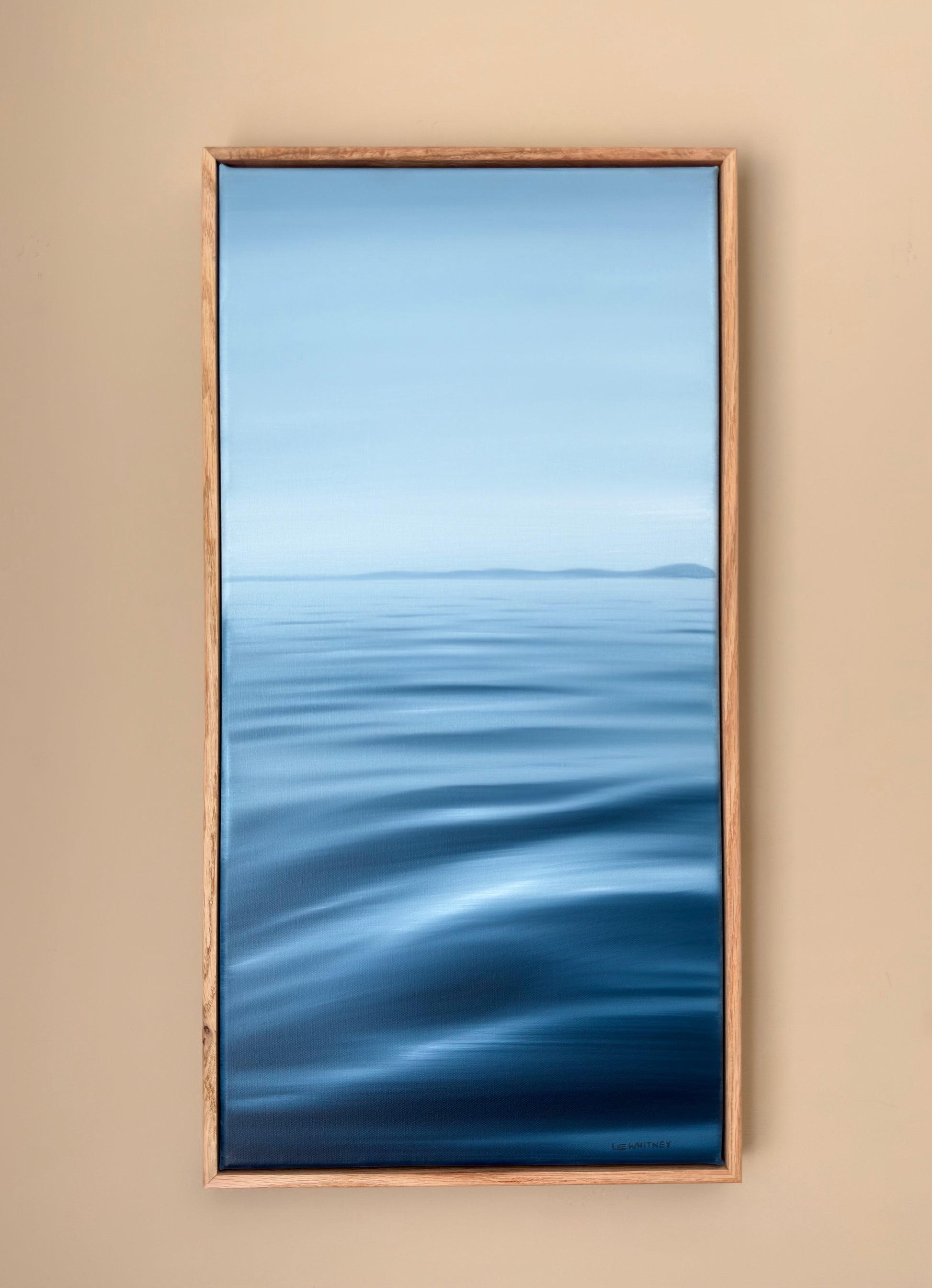 Framed artwork of a blue abstract landscape on a beige wall