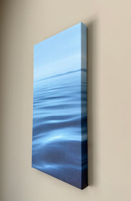 Rectangular canvas print of a blue waterscape design on a beige wall