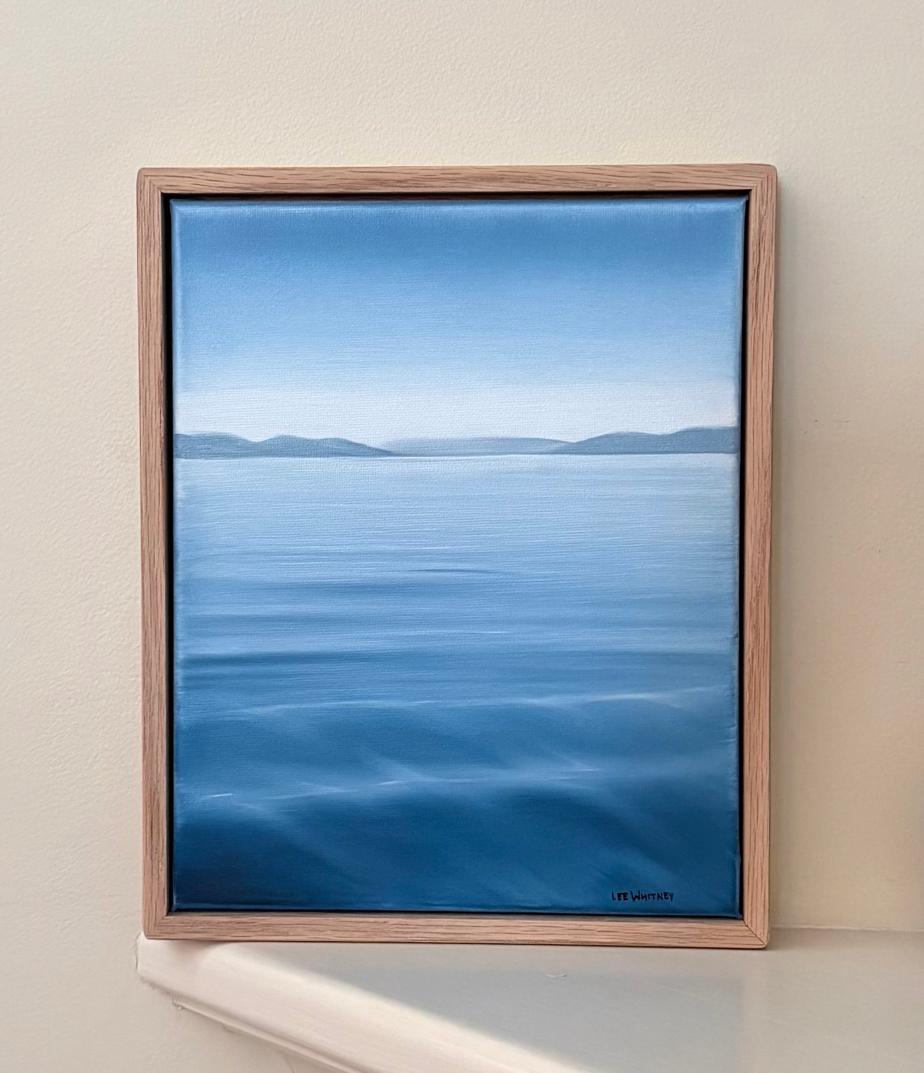 Framed artwork of a blue landscape on a beige wall