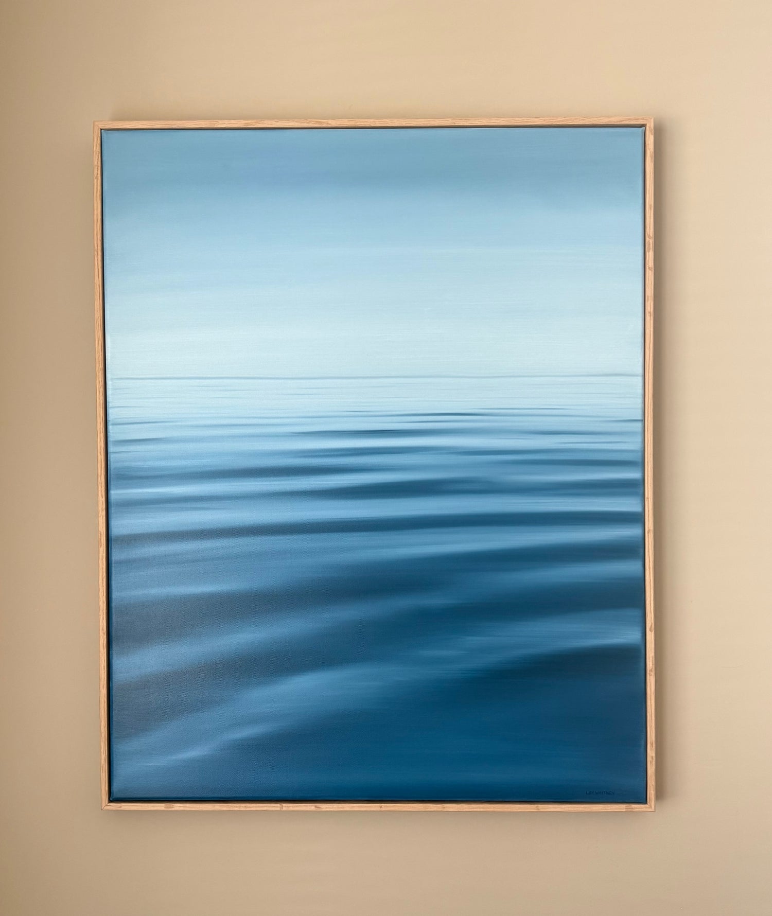 Framed abstract artwork with blue gradient on a beige wall