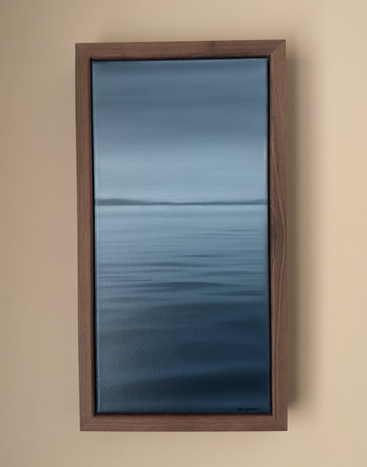 Framed artwork of a blue abstract waterscape on a beige wall