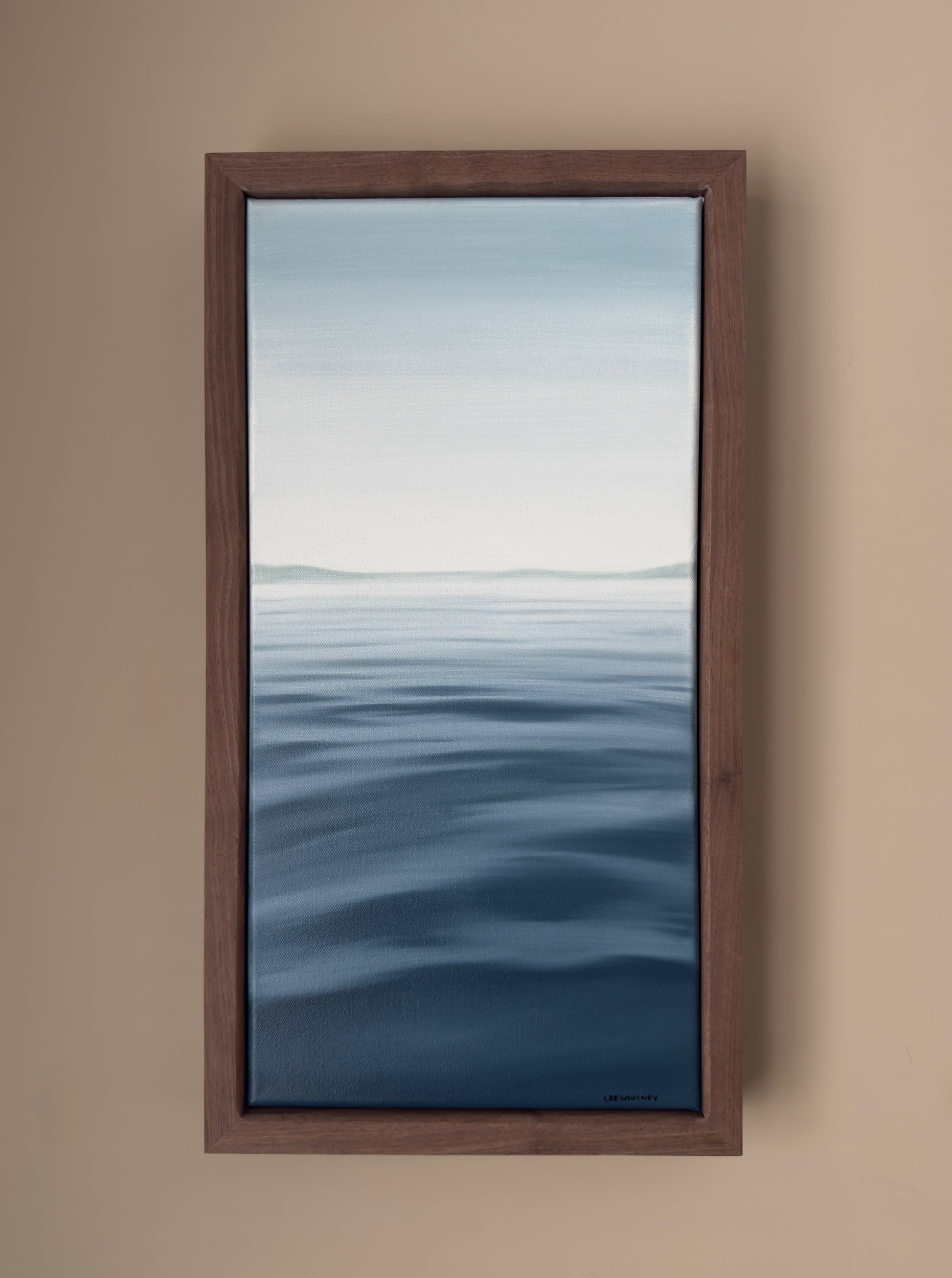 Framed artwork of a water scene on a beige wall